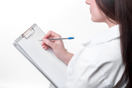 Detail of female doctor writing on clipboard, isolated on white backgroundの写真素材