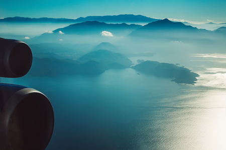 Sea and mountains view through airplane window at high altitudeの写真素材