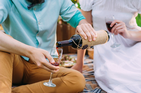 a man pouring red wine to his wine glass after he had filled hersの写真素材