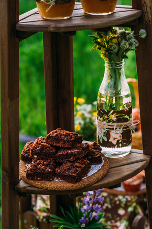 Some freshly cut chocolate cake slices next to a decorated glass bottle with cute wildflowersの写真素材