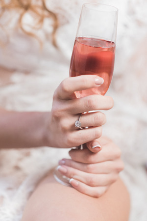Bride beautiful hands holding a glass of pink champagneの写真素材