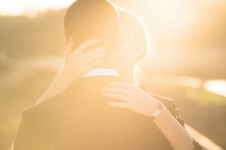 Warm lighted photo,woman's hands embracing man's neck and shouldersの写真素材