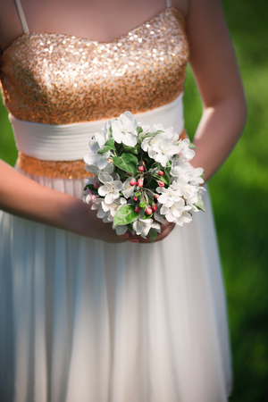 White flowers bouquet in the elegant female hands of a girl in a light white dressの写真素材