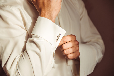 Man in a neat white shirt fixing nice cufflinks carefully on the shirt cuffsの写真素材