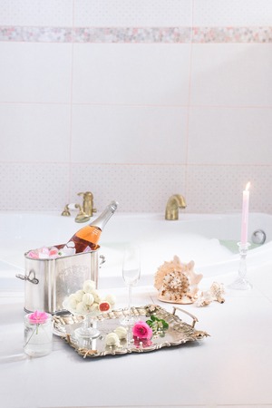 Bubble bath with champagne, red velvet cupcakes and seashell decorations, clean and pinkyの写真素材