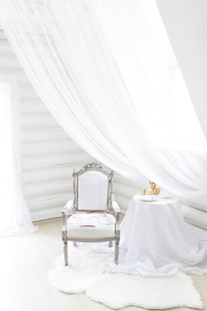 Blinding white interior, an old fashioned rich chair and a light curtain above itの写真素材