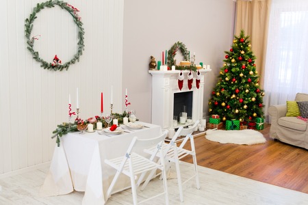 Homelike cozy place Christmas decorations, New Year tree and a nice table for two, pine branches and red color contrasting with white. Christmas or New Year's interiorの写真素材