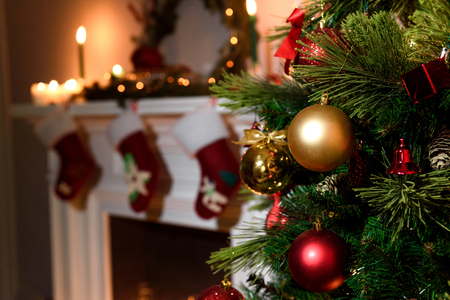Beautiful decorated fireplace and Christmas tree at cottage. A rich christmas tree with lots of hanging toys and a candled fireplace blurred on the backgroundの写真素材