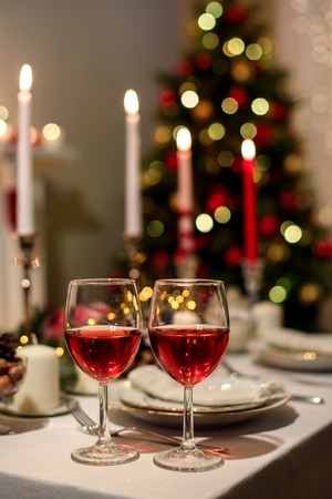 Served holiday table with two wine glasses, blurred new year decorations on the background. Christmas And New Year Holiday Table. Beautiful Christmas table settingの写真素材