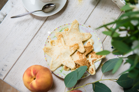 Fried pancakes on white wooden table, top view. Space for text. A cute plate of originally backed star-shaped pancakes on a white wooden backgroundの写真素材