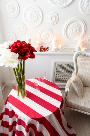An upper view on a red stripped table with fresh and bright contrasting flowers in a glass vaseの写真素材