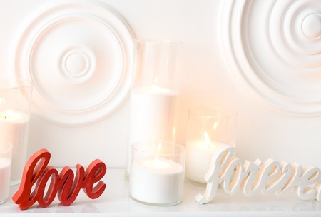 White composition of burning candles and love forever written in a colored woodの写真素材