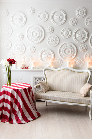 Beautiful modern living room with sofa. A romantic atmosphere in a light white room with a bright table and a cozy sofa in itの写真素材