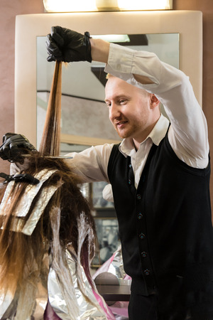 Stylist with hair dye and brush coloring hair at salon. A picture of a cool hairdresser brushing his client's hair in a specific wayの写真素材