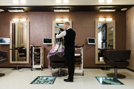 Hairdresser's salon with one client being served, black chairs and huge clean mirrors. Beauty and people conceptの写真素材