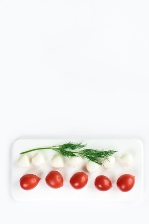 Top view of a fresh contrasting picture of a duet of small tomatoes and expensive cheese isolated in white, copy space. Healthy foods, cooking and vegetarian concept summer vegetables borderの写真素材