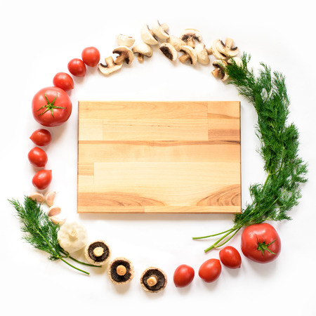 Vegetables around empty cutting board on white background, top view. Creative and national cuisine and cooking concept. A perfect circle of vegetables for a traditional Italian dish, juicy colorsの写真素材