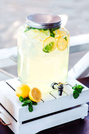 Close up of picnic party in park drink table with large pitcher filled with ice cold lemonade and...