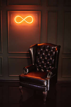 Black vintage leather armchair boss on a green background with neon signの写真素材