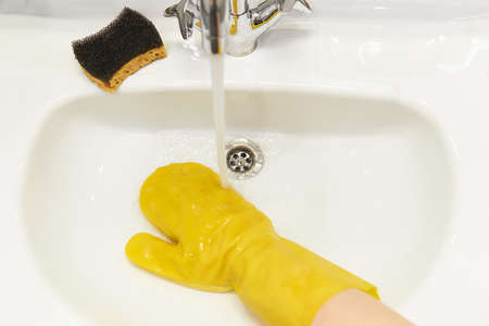 Woman hand cleaning desinfected sink and water tap. Coronavirus cleaning and disinfection recommentation guidelines to clean and disinfect sinks.の写真素材