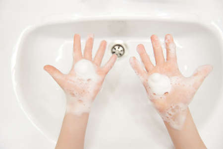 Splayed children's hands with soapy foam. Hygiene concept hand detail. Free space for text. Copy...