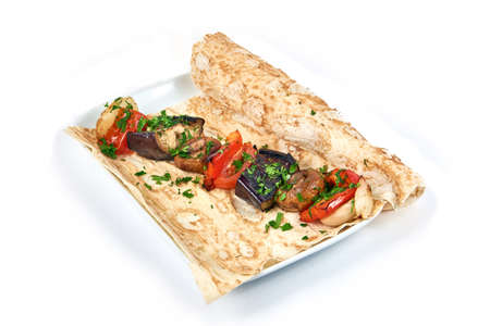 Baked vegetables on a pita bread on a white plate in a restaurant. Stay home and cook concept. Country style food. Close up view. Isolated on white backgroundの写真素材