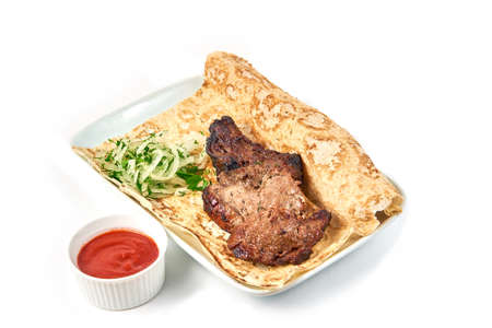 Pork skewers on the bone with sauce in a restaurant close-up. Skewers with onions and pita bread on a white plate and white background. Isolatedの写真素材