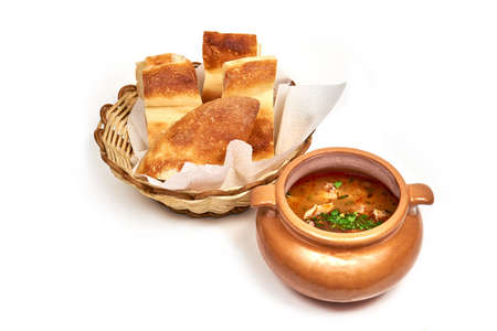 Clay pot of soup served with a slice of bread. Serving dishes in a cafe, restaurant, for a menu. Isolated on white backgroundの写真素材