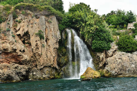 Small waterfall from green roks meets the Mediterranean seaの写真素材