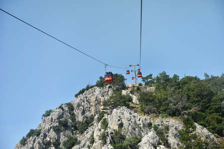 Cable car in summer mountains. Orange cable car among green mountains. Horizontal color photography.の写真素材
