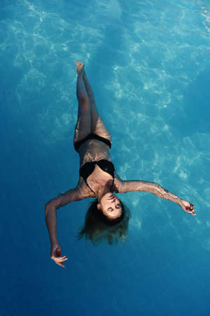 High angle view of attractive woman relaxing in the water with closed eyes. Portrait of happy woman in bikini floating in a water.の写真素材