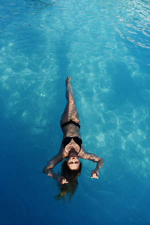 Top view of beautiful female in swimming pool background. Floating in swimming pool at Spa Hotel in summer holidays vacation. Healthy Lifestyle. Wellness, Beauty, Health Concept. Time to relax.の写真素材