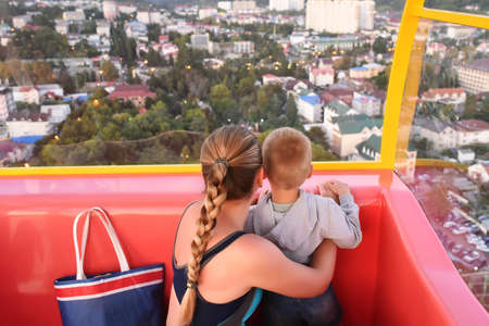 Mother and son enjoying the view from ferris wheel in amusement parkの写真素材