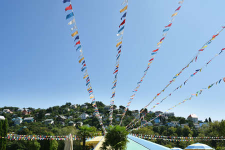 Multi-colored flags in the sky against the background of a small town. Festival party event, summer holiday feast celebration, carnival concept.の写真素材