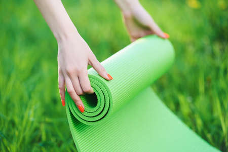 Close up hands unrolling bright green exercise mat.の写真素材