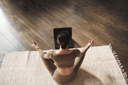 Top view young sporty slim woman doing easy yoga practice at home, stress relaxing exercise by yourself at home, stay fit by yoga with professional yoga master as your personal trainer, full length.の写真素材