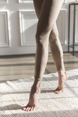 Fit long woman legs in leggings. Close up slim, slender, shapely legs in beige skin-tight sweatpants. Fashion sportswear. Sexy long pumped-up legs fitness model. Sports figure. Posing of feet.Crossfitの写真素材