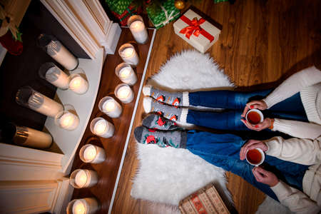 Feet in wool socks of couple lovers warming by cozy fireplace in winter time.の写真素材