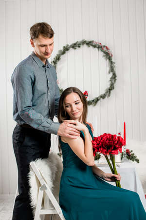 A gentle picture of an elegant girl with a red bouquet being hugged by her husband.の写真素材