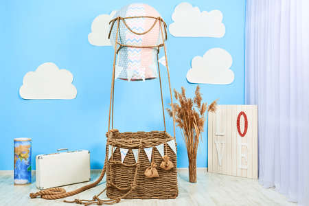 Interior room for a boy. White clouds fly toy basket of balloon. Air balloon at solid color background with copy space.の写真素材