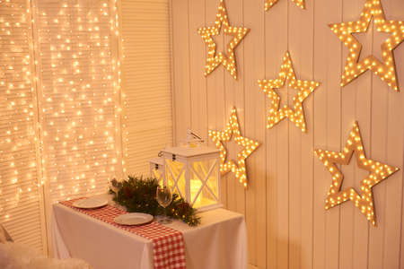 Dining room decorated for Christmas. Table with chairs set, waiting for guests. The wall is decorated with luminous stars, Xmas Home Interior. Beautiful New Year decorated classic home interiorの写真素材
