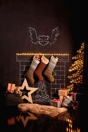 New Year's decor and tree in children's playroom. Decorated Christmas room with a beautiful tree. Painted fireplace, it weighs socks with gifts. Beautiful New Year photo area, vertical photographyの写真素材