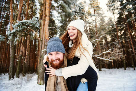 Couple in a winter forest. Background with text space for your promotion or web site about traveling during cold season. Winter holiday lifestyle romantic relationship concept. Weekends out of town.の写真素材