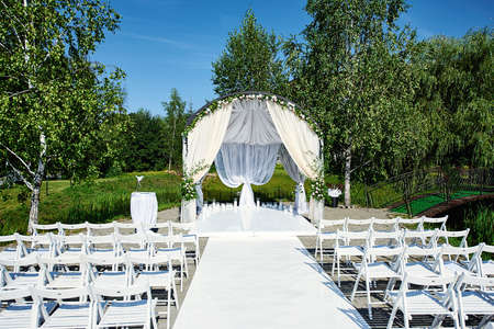Beautiful wedding decoration. The area of the wedding ceremony. Round classical arch, white chairs. Summer field registration.の写真素材