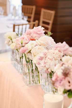 Lush floral arrangement of white and pink fresh flowers and greenery on wedding table for newlyweds. Beautiful flowers on table with white cloth, free space. Vertical photographyの写真素材