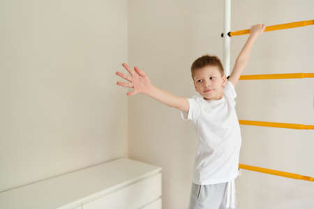 Cute smiling boy doing morning exercise. Childhood, happiness, active lifestyle, Physical, Hand and Eye Coordination, Sensory, Motor Skills development, Home workout concept. Focus on hand.の写真素材