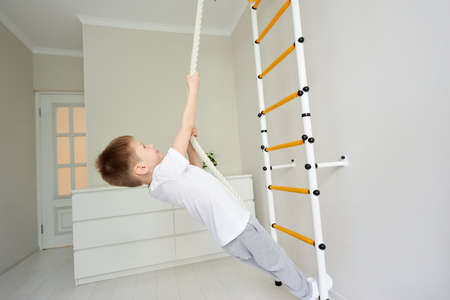 Handsome schoolboy wearing white t-shirt and gray sweatpants resting their feet on the bar wall...