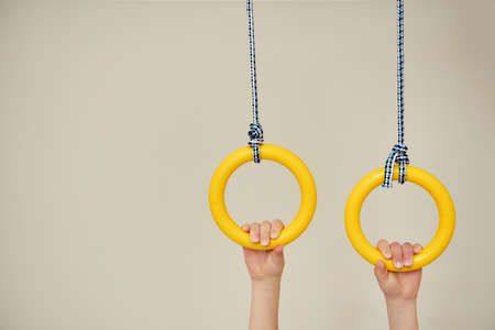 Image with space for text children's hands holding gymnastic rings. Arm muscle training. Childhood, Physical, Hand Coordination, Sensory, Motor Skills development conceptの写真素材