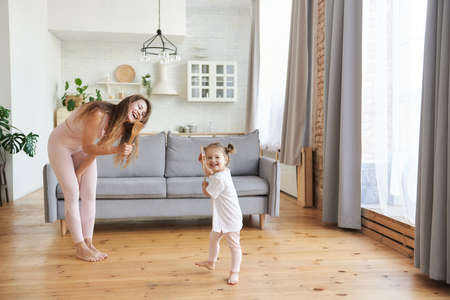 Happy mother's day! Young mom or nanny play sing entertain using kitchen appliances with little preschooler girl child, overjoyed mother have fun enjoy family leisure weekend with daughter at home.の写真素材