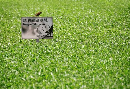 Keep of the Grass sign in English and Chinese, with sparrow perched on top, Hong Kong の写真素材